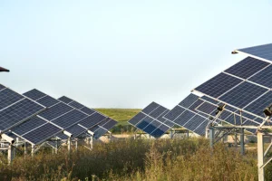 Installateur local en train de poser un panneau solaire avec vue sur la campagne normande